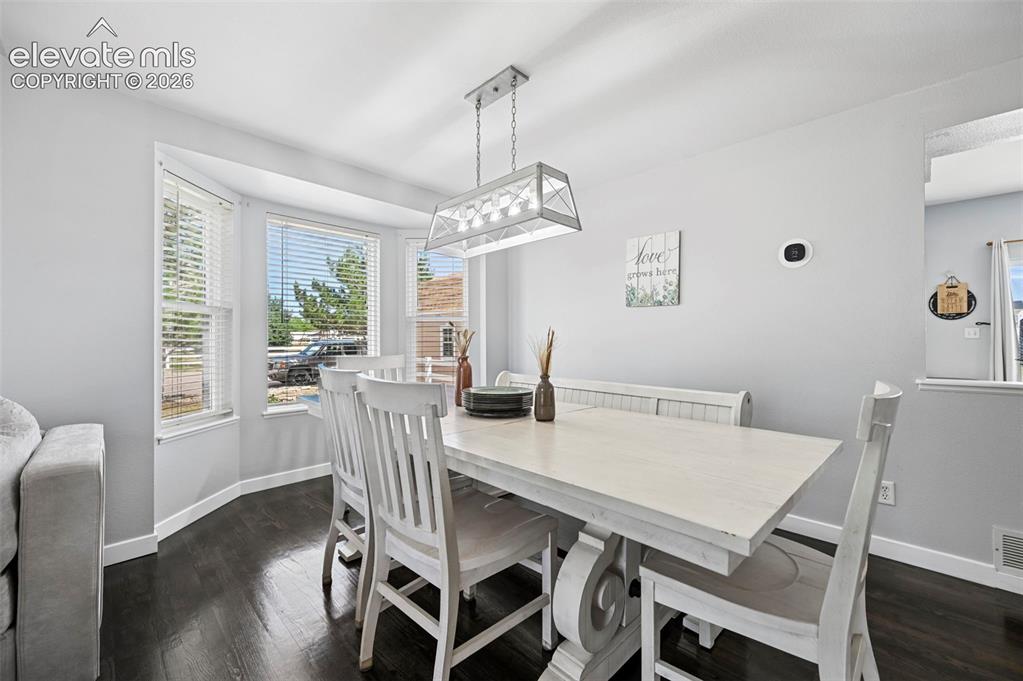 Image 27 of 37: Dining area featuring a bay window, dark wood-finish flooring, and a white