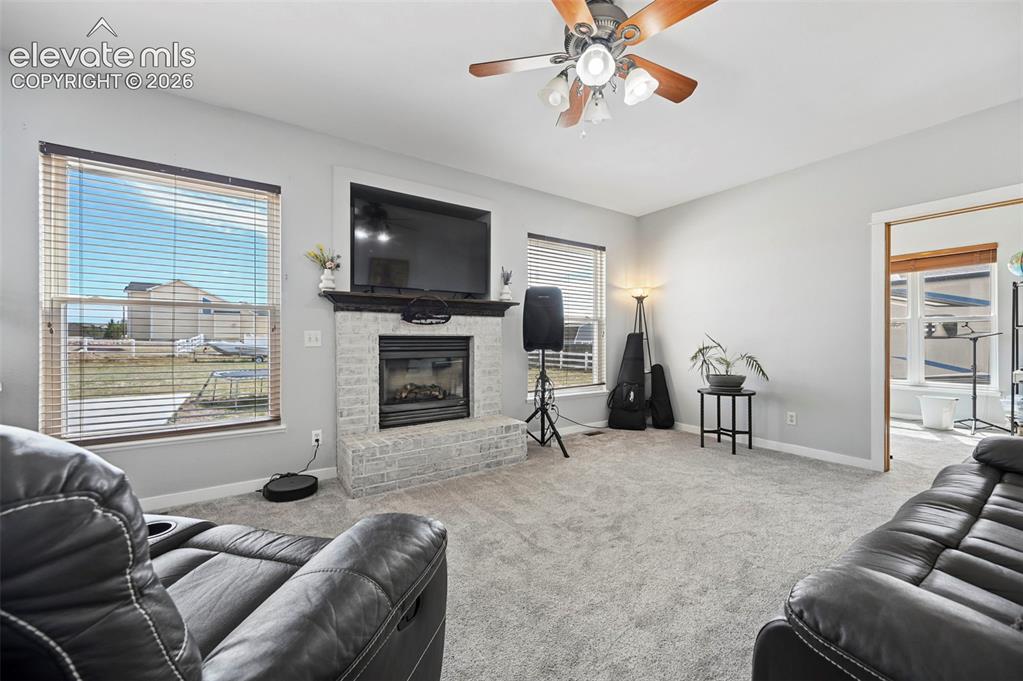 Image 3 of 37: Living space featuring a light gray brick fireplace with a dark mantel, a c