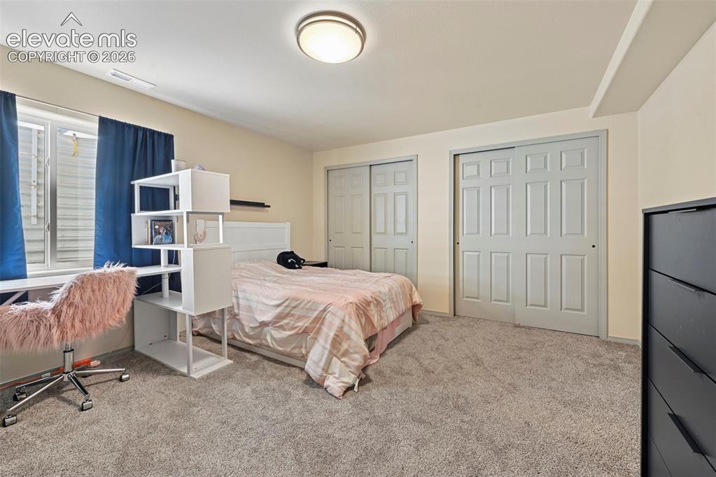 Image 9 of 37: Spacious carpeted room featuring two panel sliding closet doors, a window w