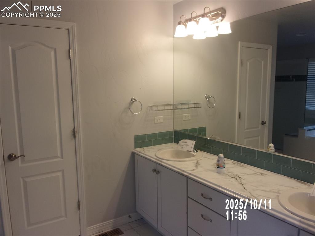 Image 18 of 21: Bathroom with double vanity and light tile patterned flooring