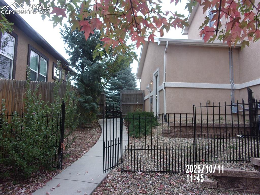 Image 21 of 21: View of side of property featuring stucco siding and a gate