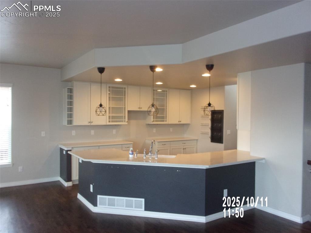 Image 6 of 21: Kitchen with decorative light fixtures, white cabinets, glass insert cabine