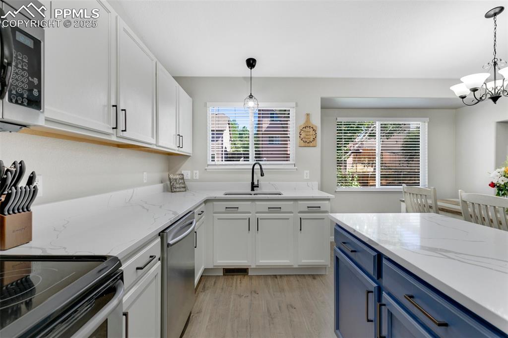 Image 11 of 27: Kitchen featuring blue cabinets, white cabinetry, light wood-style floors, 
