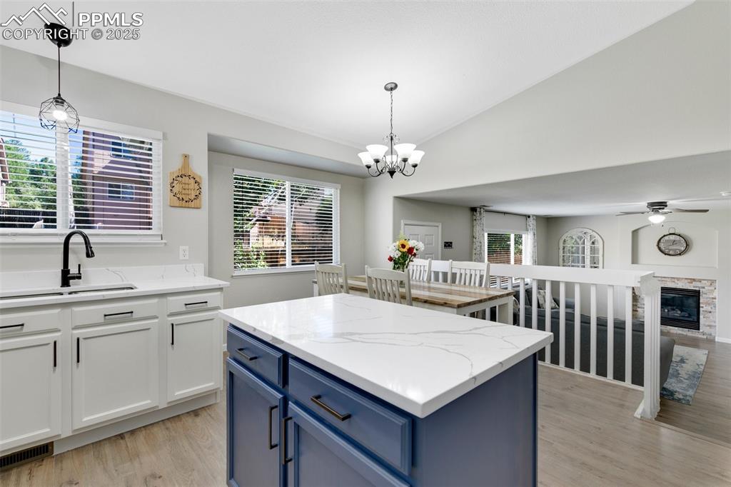 Image 12 of 27: Kitchen with blue cabinetry, white cabinetry, light wood-style floors, hang