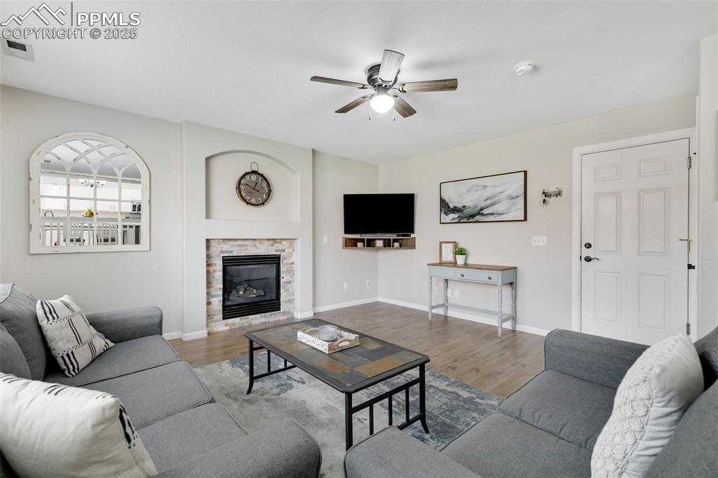 Image 15 of 27: Living area featuring a glass covered fireplace, wood finished floors, and 