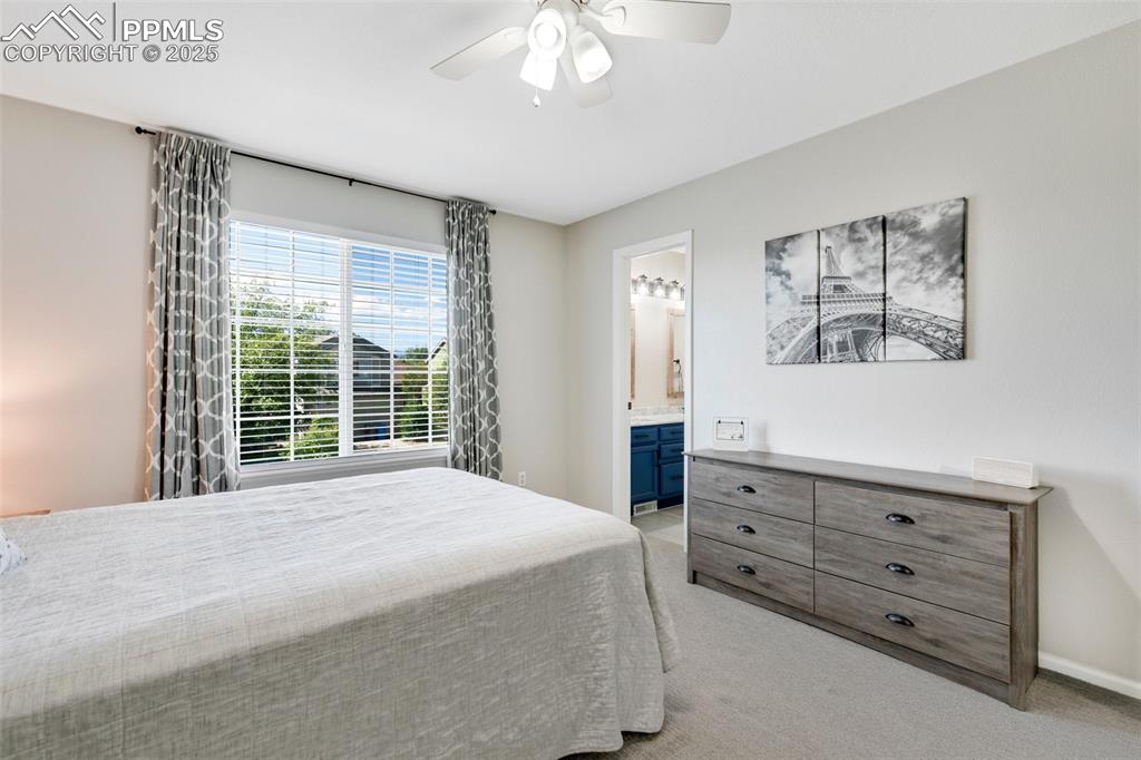 Image 21 of 27: Bedroom with light carpet, a ceiling fan, and ensuite bath