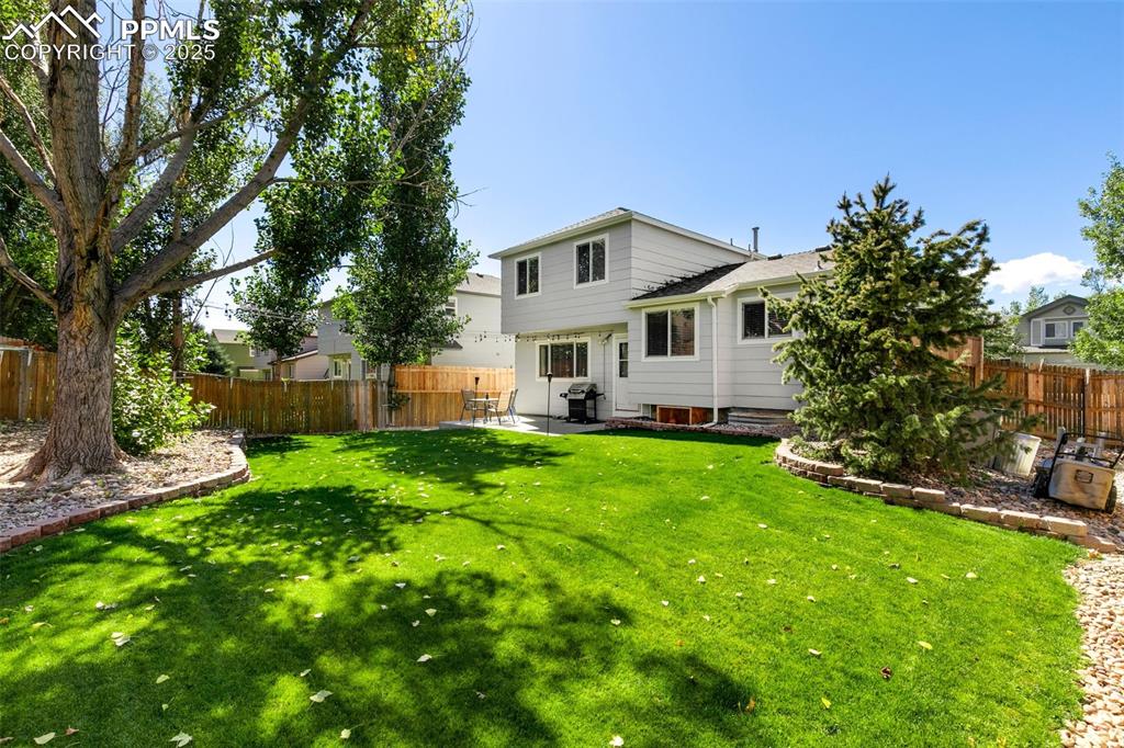 Image 27 of 27: Rear view of house with a fenced backyard and a patio