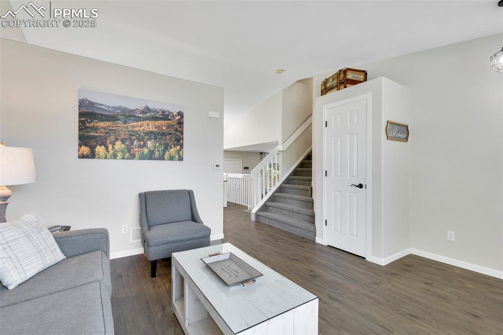 Image 6 of 27: Living area featuring stairway and dark wood finished floors