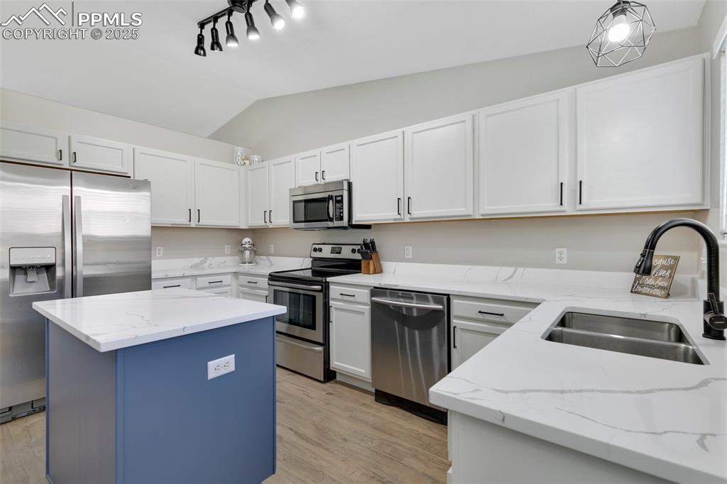Image 9 of 27: Kitchen featuring lofted ceiling, appliances with stainless steel finishes,