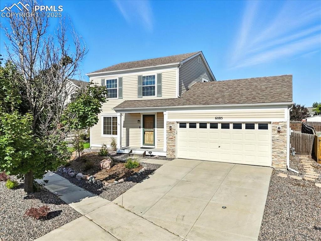 Caption: View of front of property with a garage, concrete driveway, roof with shingles, and stone siding