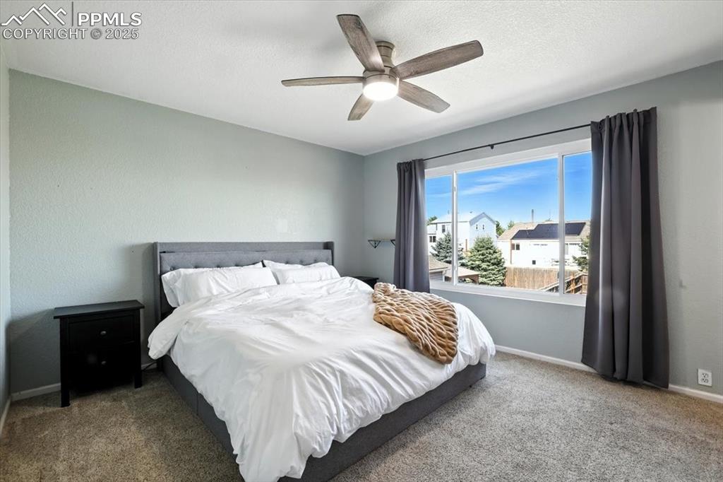 Image 11 of 33: Bedroom with carpet, a textured ceiling, and ceiling fan