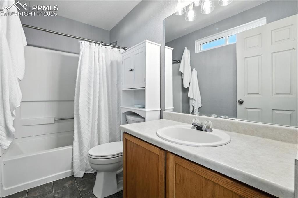 Image 13 of 33: Bathroom with vanity, shower / bath combo, and dark tile patterned floors