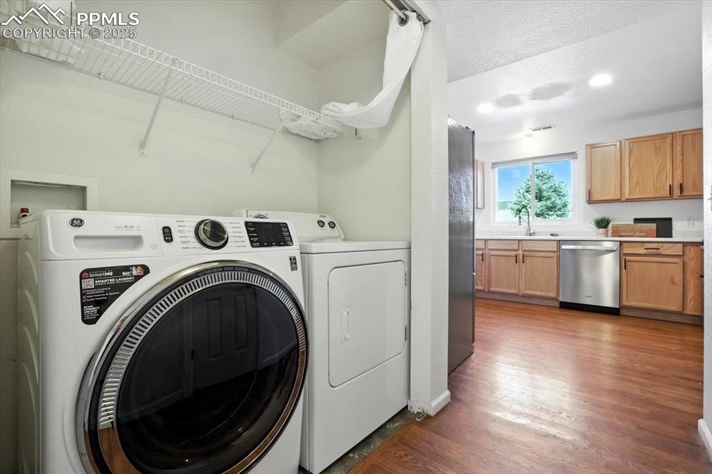 Image 14 of 33: Laundry area with a textured ceiling, wood finished floors, and separate wa