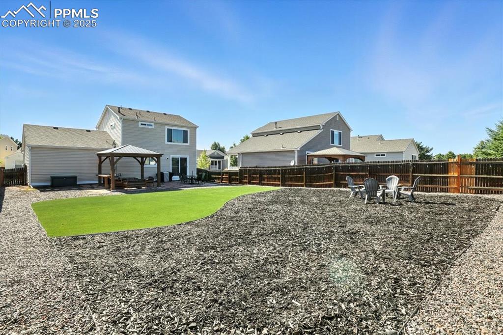 Image 26 of 33: Fenced backyard featuring a gazebo, a patio area, and an outdoor fire pit