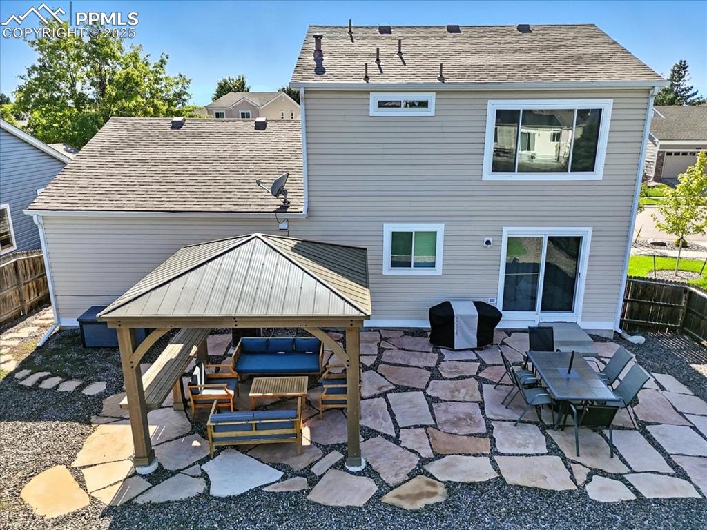 Image 27 of 33: Back of property featuring a patio area, a shingled roof, and a gazebo