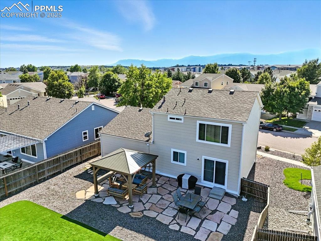 Image 29 of 33: Rear view of house featuring roof with shingles, a patio, a residential vie