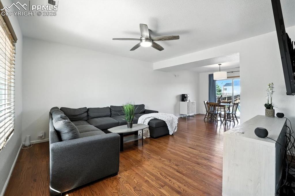 Image 3 of 33: Living room featuring dark wood-style floors and a ceiling fan