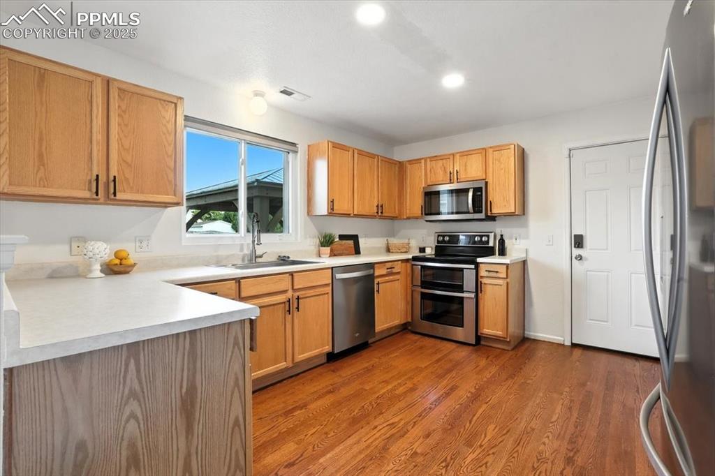 Image 7 of 33: Kitchen with appliances with stainless steel finishes, light countertops, d