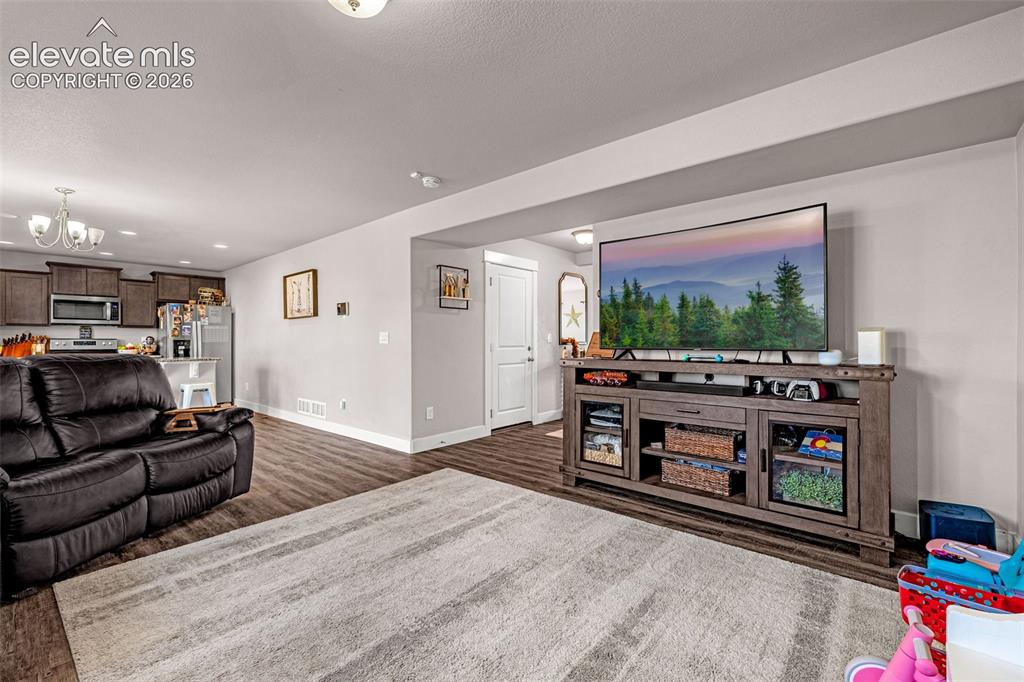 Image 12 of 37: Spacious open-concept living area featuring wood-finish flooring, recessed