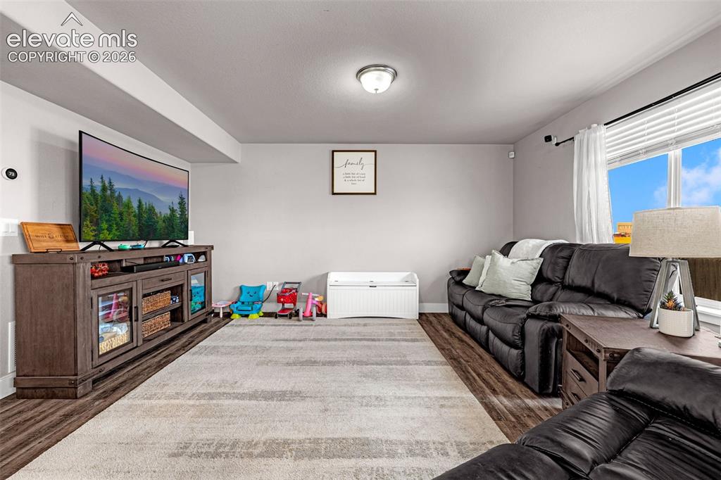 Image 13 of 37: Spacious room featuring wood-finish flooring, light gray walls, and a large