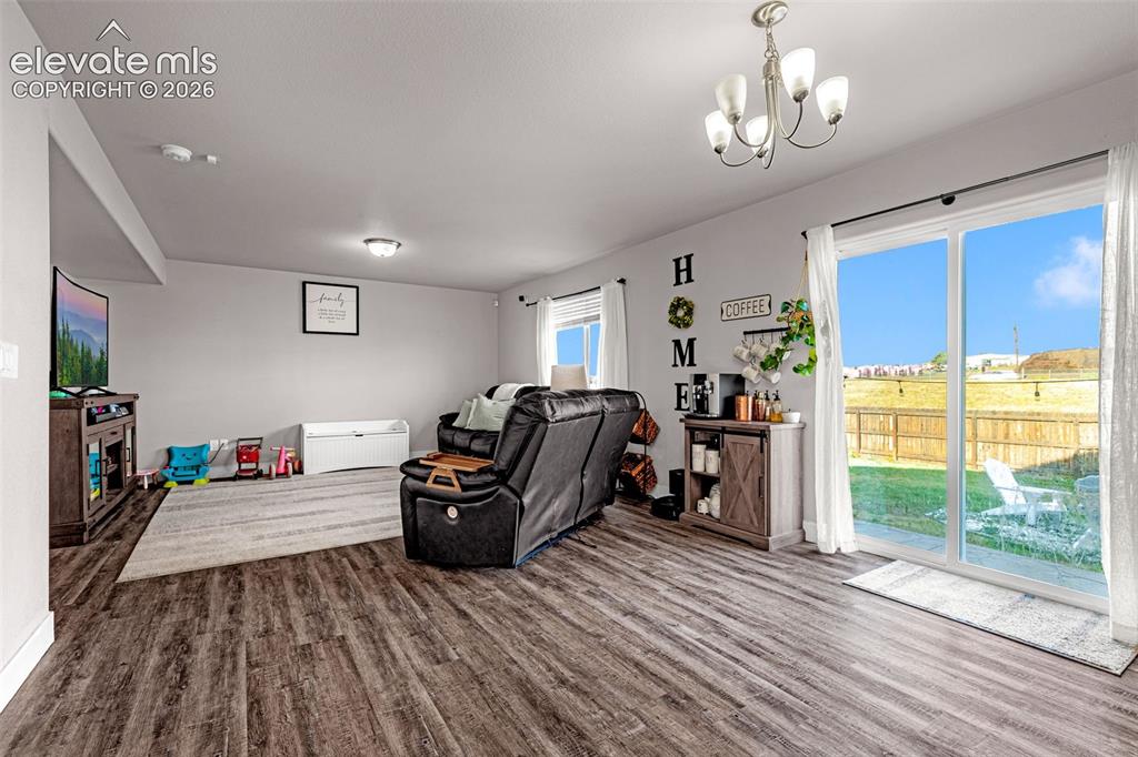 Image 14 of 37: Spacious living area featuring wood-finish flooring, light grey walls, and