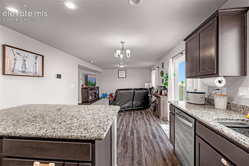 Image 15 of 37: Open-concept living area featuring a kitchen island with granite-finish cou