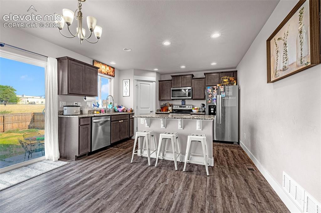 Image 16 of 37: Open-concept kitchen featuring wood-finish flooring, dark wood cabinetry, s