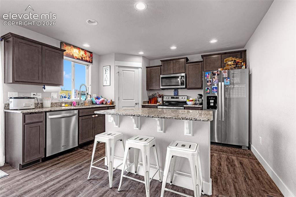 Image 17 of 37: Modern kitchen featuring wood-finish flooring, dark wood cabinetry, and spe