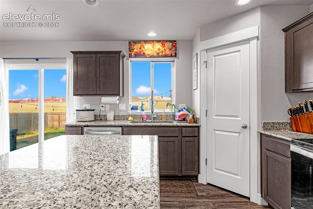 Image 18 of 37: Kitchen featuring a stone-look countertop island, dark wood-finish cabinetr
