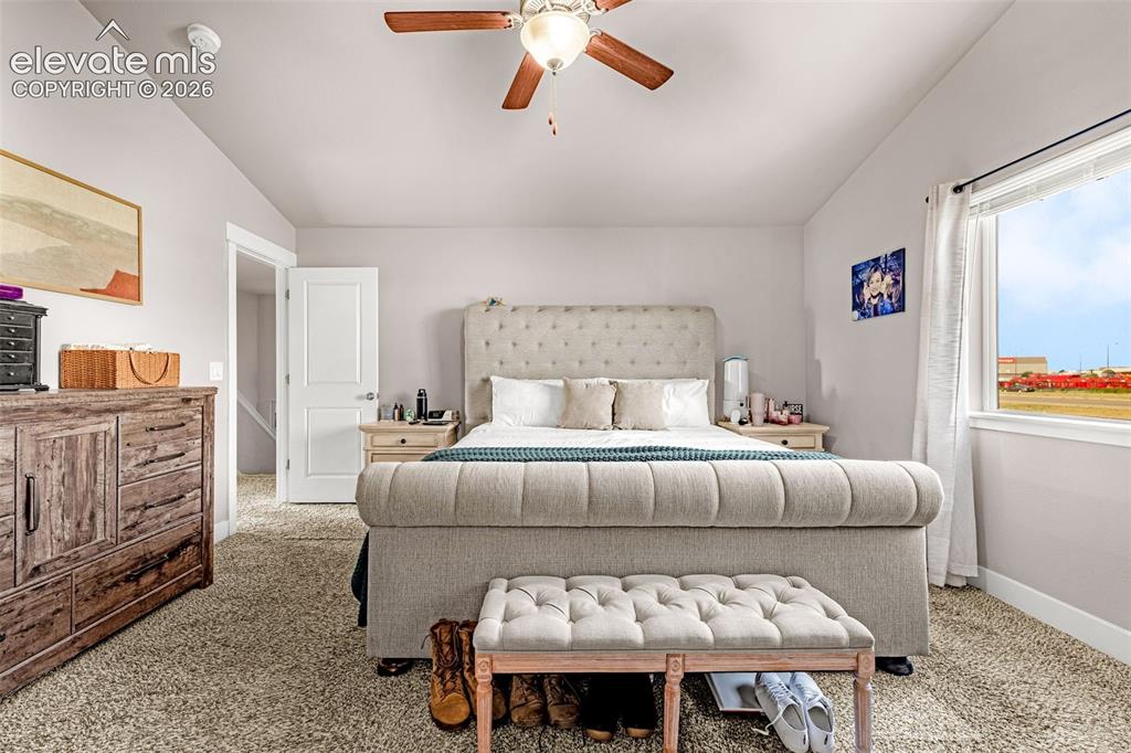 Image 19 of 37: Carpeted room with a ceiling fan, white trim, and a window with a white fra