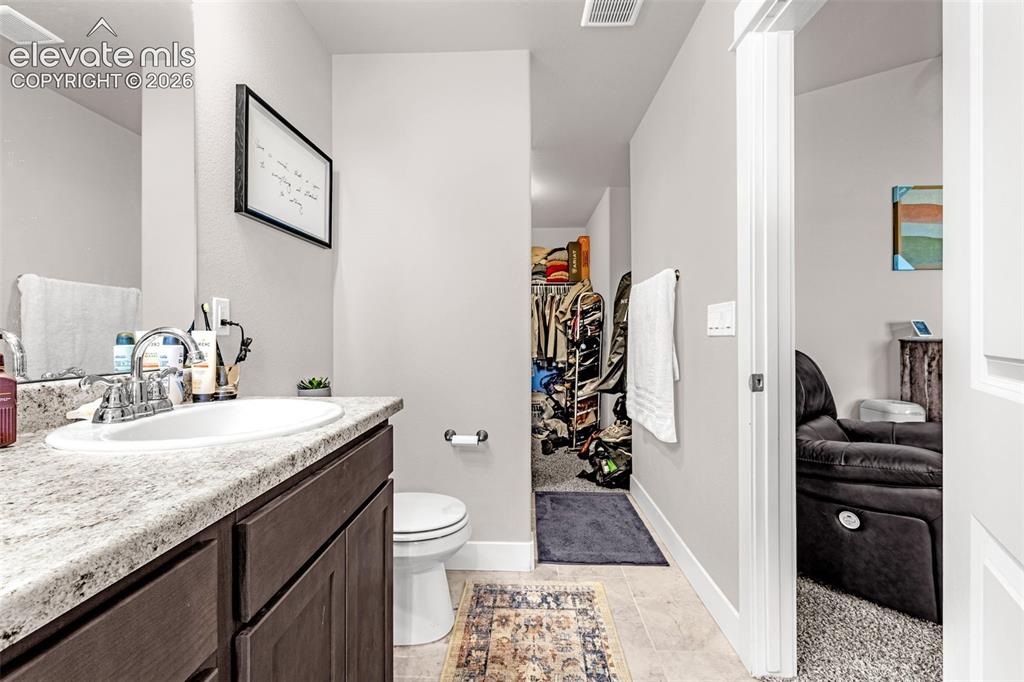 Image 24 of 37: Bathroom featuring a wood-finish vanity with a light speckled countertop, u