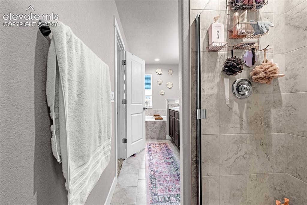 Image 26 of 37: Glass-enclosed shower with large format tile surround and chrome fixtures