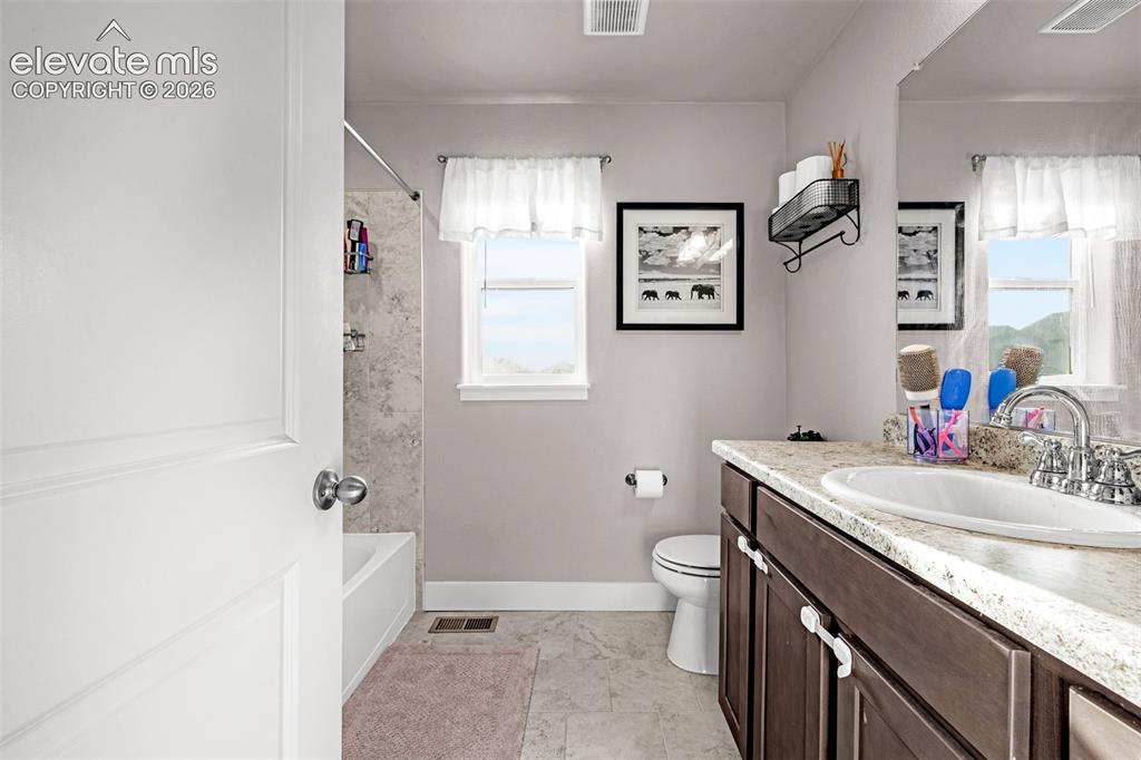 Image 28 of 37: Bathroom featuring a white bathtub with a tiled shower surround, a window w