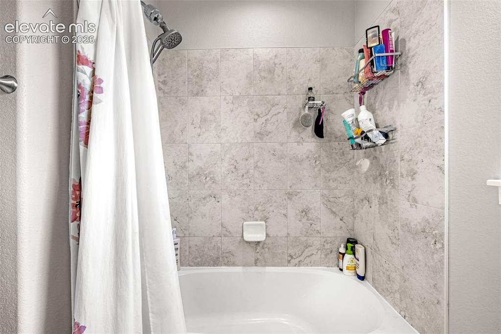 Image 29 of 37: Bathtub and shower combination featuring neutral-toned tile surround