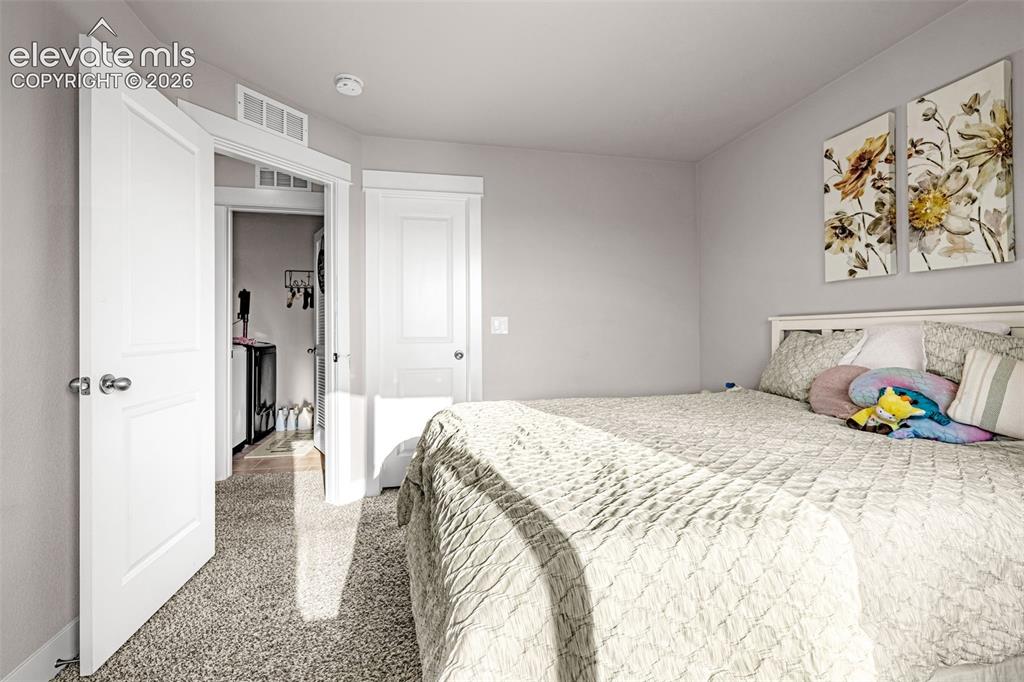 Image 31 of 37: Neutral toned bedroom featuring light grey walls, white trim, and textured