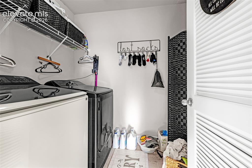 Image 33 of 37: Dedicated laundry space featuring a white louvered door, tile flooring, and