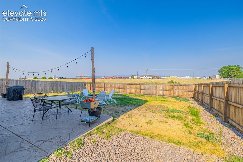 Image 34 of 37: Expansive backyard featuring a concrete patio with string lighting, a grave