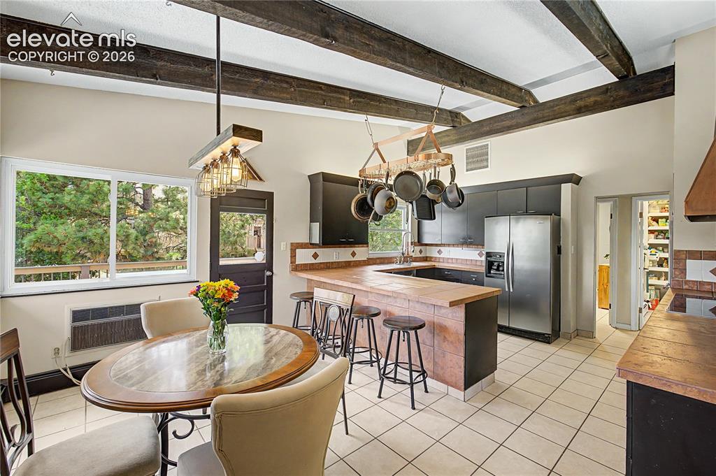 Image 12 of 50: A sunlit breakfast nook, framed by corner windows and exposed wood ceiling