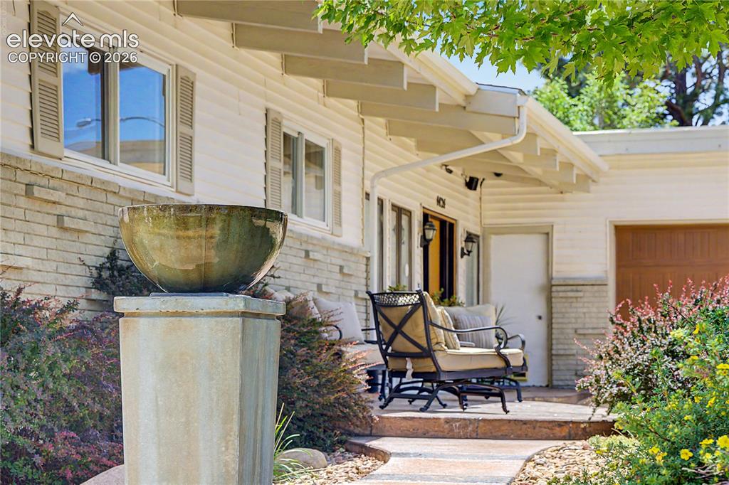 Image 2 of 50: A stone pedestal fountain greets visitors at the front porch, where exposed