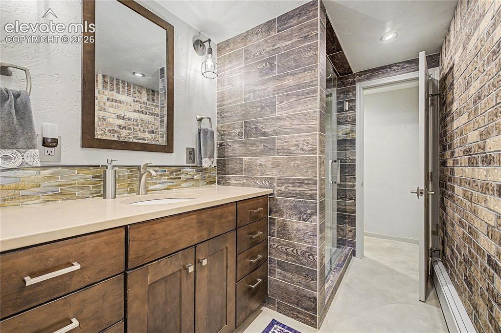 Image 25 of 50: A secondary bath features a wood-look tile walk-in shower and glass-mosaic