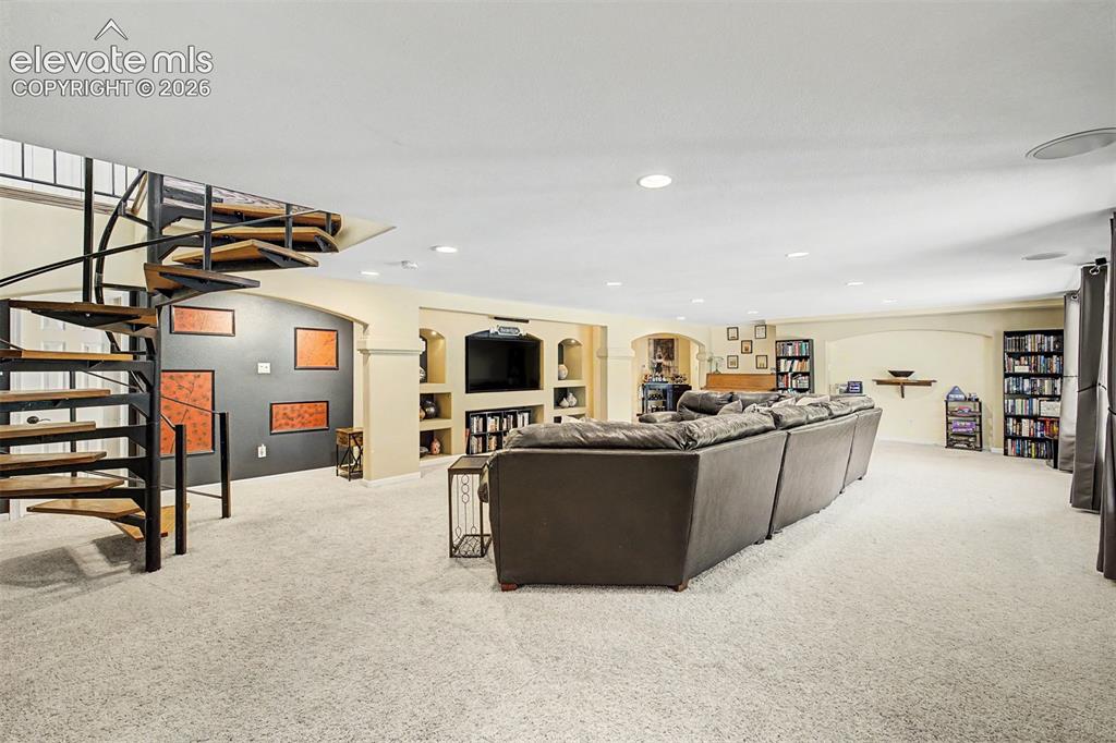 Image 27 of 50: A dramatic spiral staircase connects this expansive lower-level living room