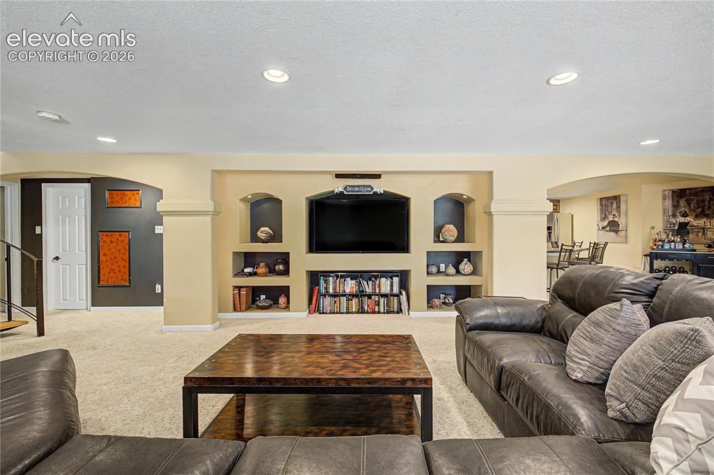 Image 29 of 50: A built-in media wall with arched display niches transforms the lower level