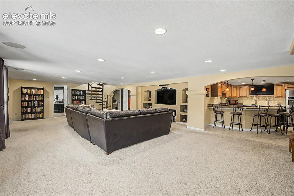Image 30 of 50: Just beyond the media area, a built-in wet bar extends the lower level into