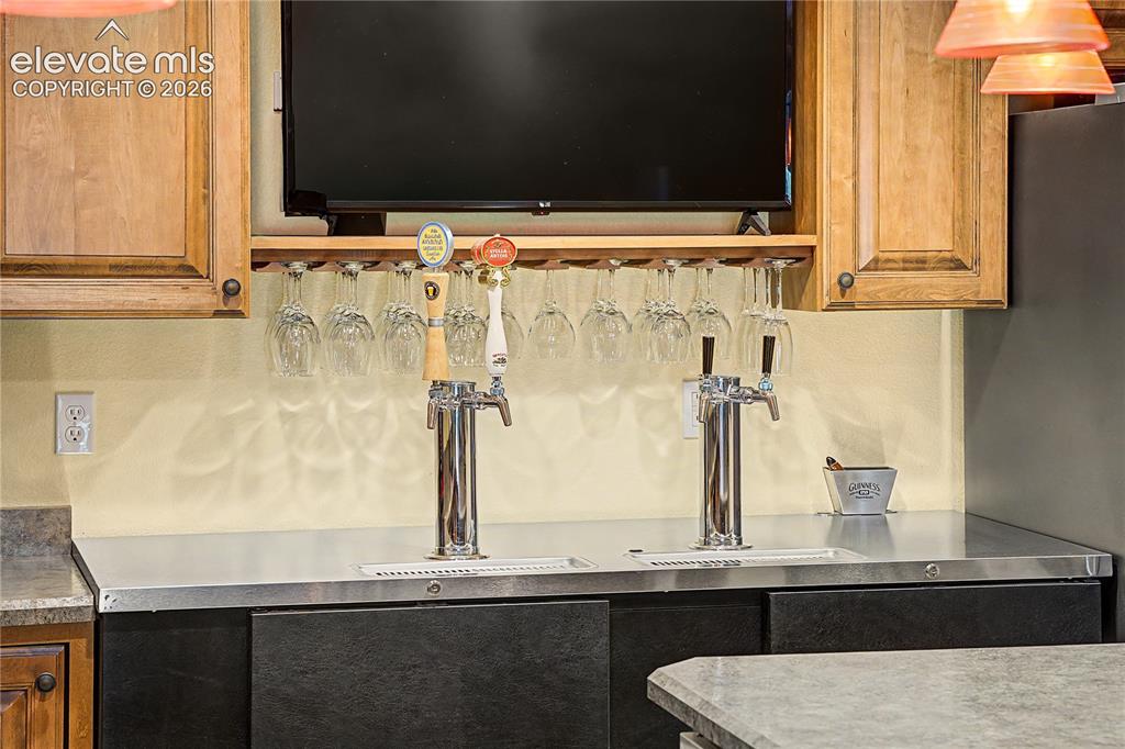 Image 32 of 50: Dual beer taps and built-in glass storage show this bar was designed with h