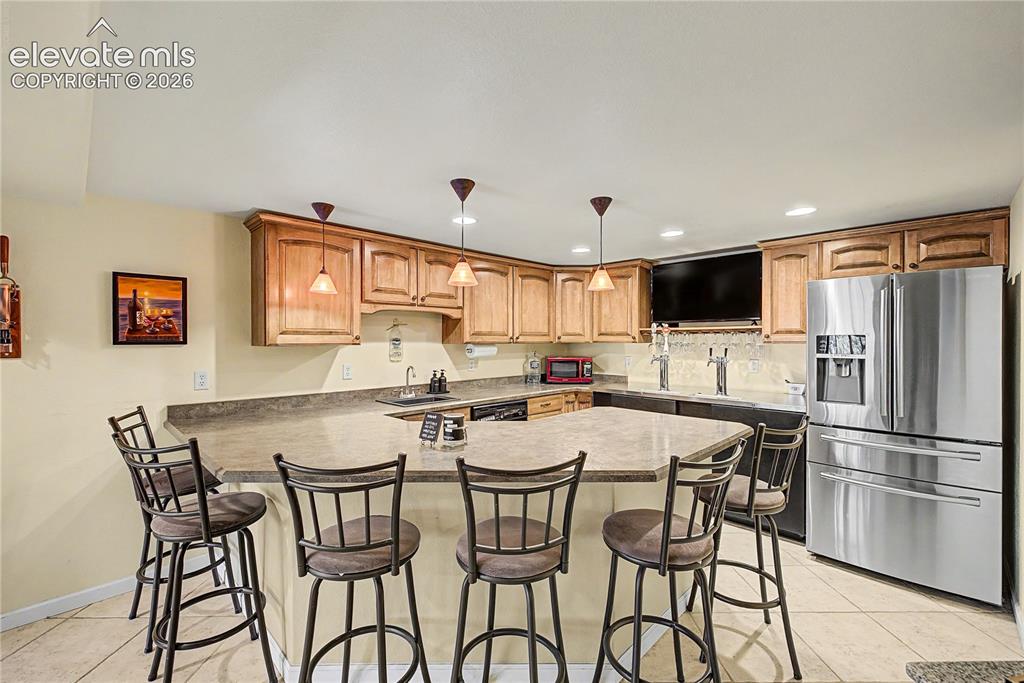 Image 33 of 50: Rounded out with a built-in refrigerator and warm wood cabinetry, the bar a