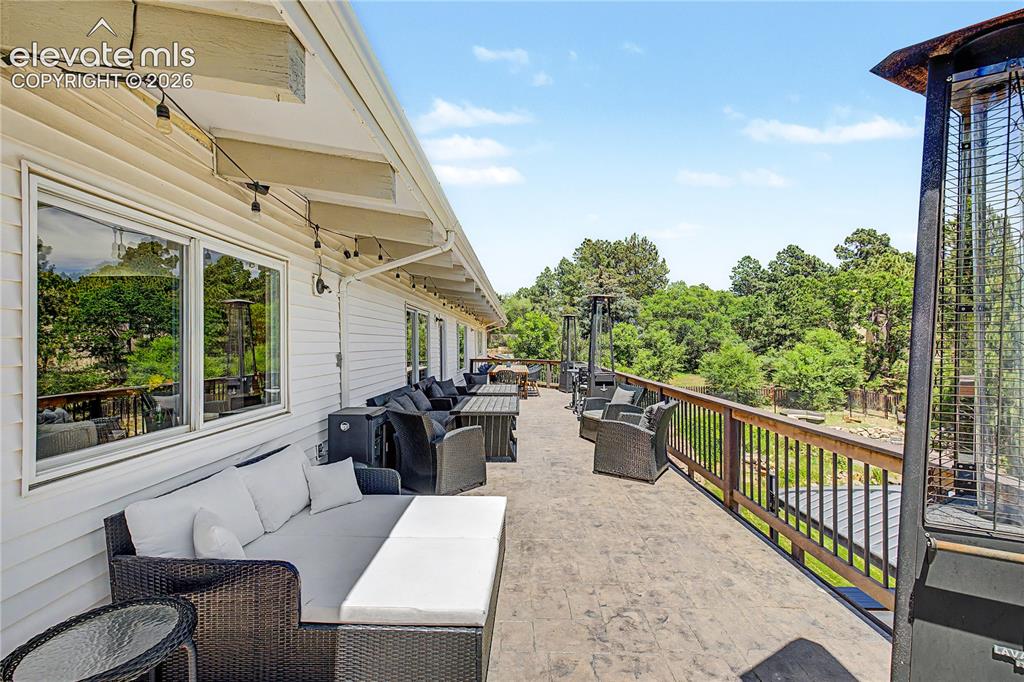Image 37 of 50: A long, stamped-stone upper deck stretches the full width of the home, stru