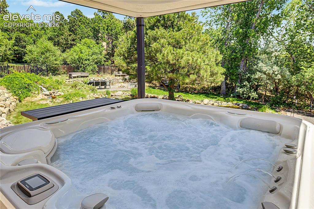 Image 40 of 50: A hot tub tucked beneath its own pergola adds a resort-like feature to the