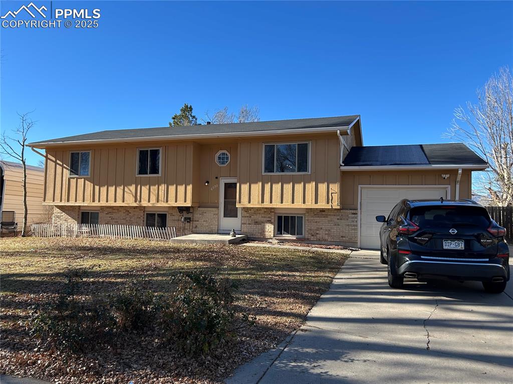 Image 1 of 1: Split foyer home featuring concrete driveway, an attached garage, brick sid