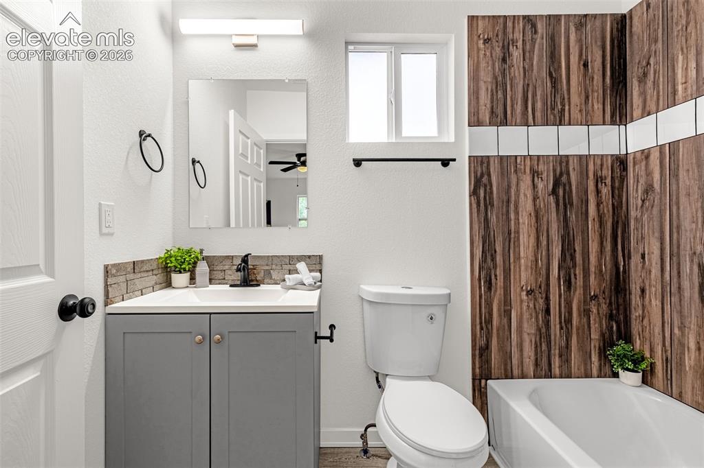 Image 10 of 50: Full bathroom featuring a white bathtub with wood-finish paneling and a til