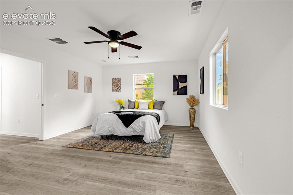 Image 11 of 50: Spacious room featuring wood-finish flooring, a contemporary ceiling fan, a